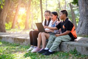 Students collaborating on a laptop outside