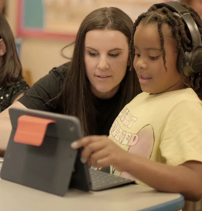 teacher helping a student use seesaw on their tablet